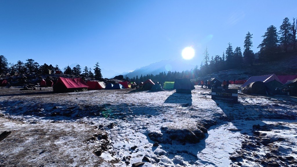 Tents on fresh snow at a Himalayan campsite as sunrise reaches the ridgeline