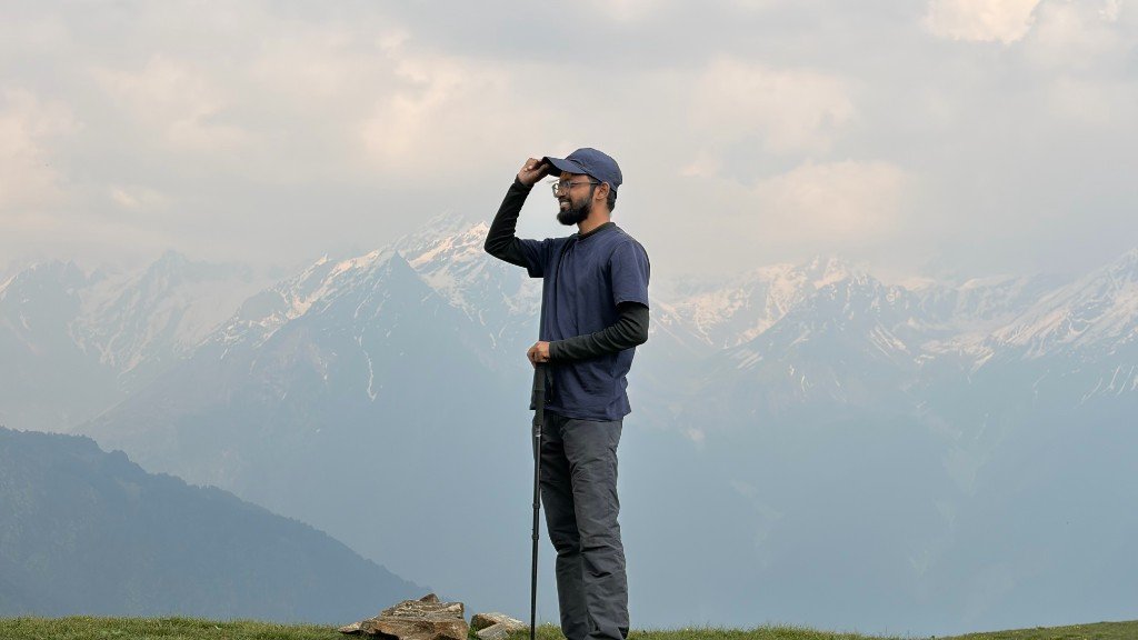 Paras standing on a grassy ridge looking towards snow-covered Himalayan peaks