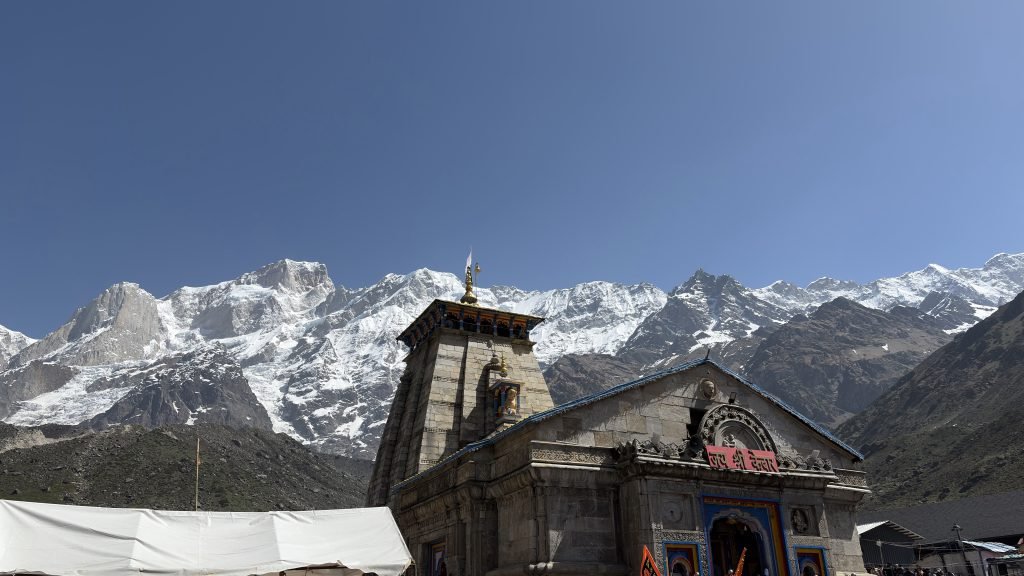 Kedarnath temple beneath snow-covered Himalayan peaks under a clear blue sky