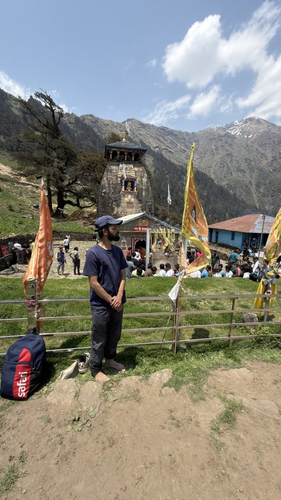 At Madhyamaheshwar temple with saffron flags and mountain ridges behind