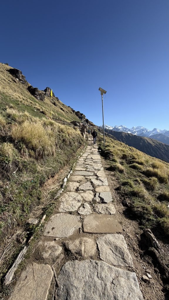Stone trail climbing toward snow peaks on the way to Rudranath