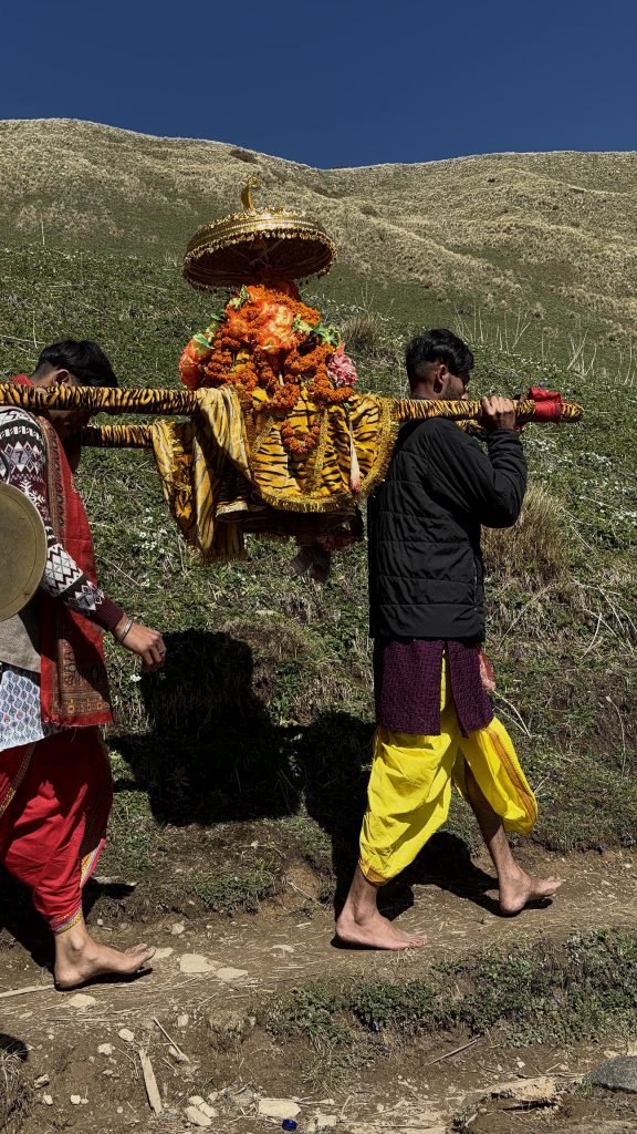 Rudranath doli carried across an alpine hillside under a clear blue sky